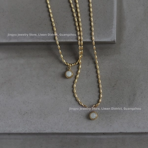 Macro shot of 18K gold plated titanium necklaces with round white stone pendants