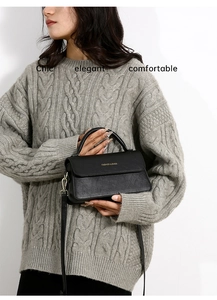 Dettaglio di una borsa a tracolla chic in pelle nera con scritta in metallo FASHION & BAGS