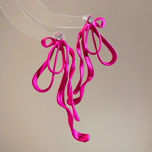 Detail of rose red bow earrings with white rhinestones and flowing design on stand