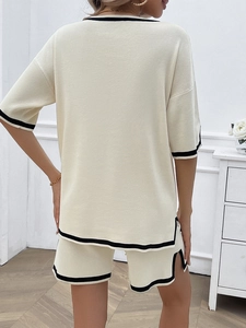 Rear view of women's beige knit sweater set featuring black trim on sleeves and hemline