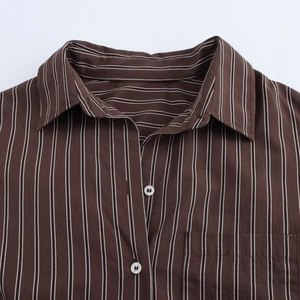 Detail view of brown striped shirt collar with white buttons and a chest pocket