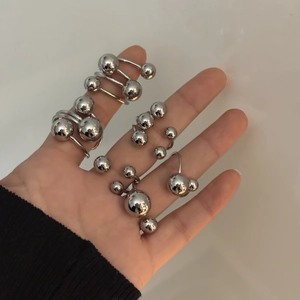 Close-up of minimalist stainless steel spherical rings in silver finish worn on model