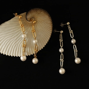Détail de boucles d'oreilles pendantes à maillons en U avec perles blanches en or et argent