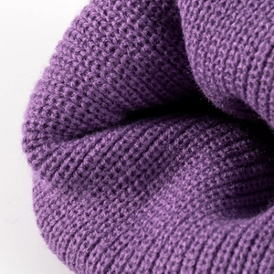 Close-up texture of a thick purple knitted beanie with fine ribbed wool pattern