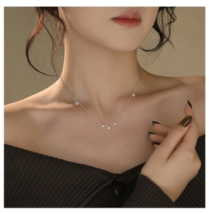 Close-up of minimalist S925 silver necklace with five sparkling zircon stones on a model