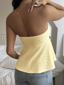 Detail view of the pale yellow sleeveless top featuring intricate hollow embroidery and ruffles