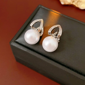 Macro shot of vintage silver earrings featuring hollow heart motifs and lustrous white pearls