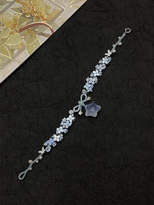 Detailed view of beaded bracelet with blue resin flowers and silver butterfly charm