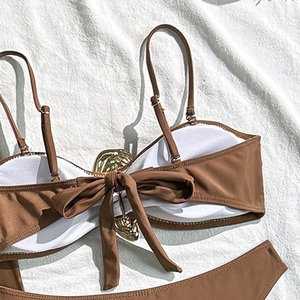 Detail of dark brown bikini top featuring a large back bow and gold wavy metal buckle