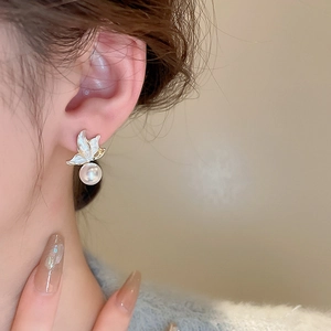 Detail shot of a butterfly pearl earring in gold finish on a model's ear