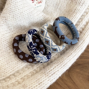 Gros plan de quatre chouchous en maille épaisse aux motifs floraux vintage et textures variées