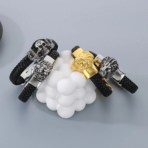 Detail of men's black braided leather bracelets with silver lion head and skull charms