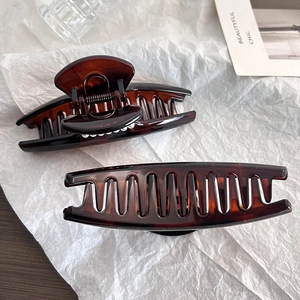 Close-up of tortoise shell pattern hair claw clips in dark amber resin with metal springs