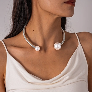 Close-up of silver geometric open torque collar with polished imitation white pearls