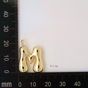 Detail view of gold puffy M letter balloon pendant showing 7.15g weight and size measurements