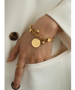 Gros plan d'un bracelet en perles dorées double couche avec pendentif Eternal Love gravé