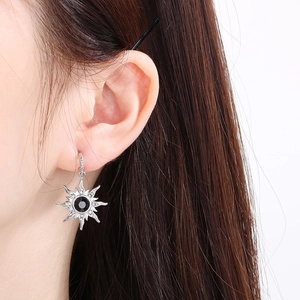 Gros plan d'une boucle d'oreille étoile argentée avec gemme noire et détails pavés
