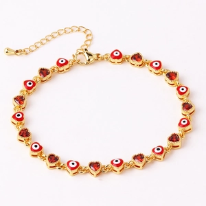 Detail of gold evil eye heart bracelet with red enamel and zircon stones on a white base