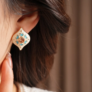 Macro shot of rhombus earring with blue enamel pattern and champagne gemstone detail