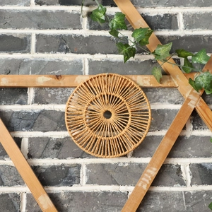 Détail d'une décoration murale ronde en rotin tressé au style bohème et fibres naturelles