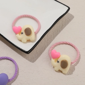 Detailed view of kids cute beige elephant hair ties with pink hearts on soft fabric