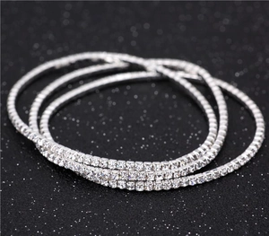 Close-up of three layered silver elastic bracelets with clear single-row rhinestones