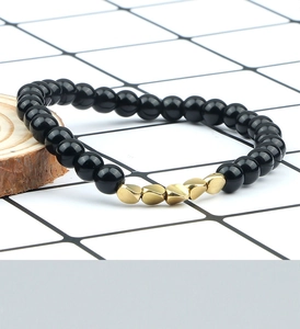 Detail of black lava stone beaded bracelet with geometric gold metallic spacers