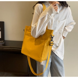 Detail view of yellow nylon tote bag featuring multi-pocket design and adjustable strap