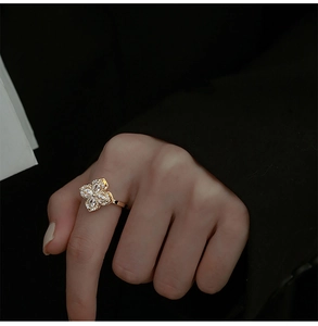 Close-up of golden spinning windmill ring with crystal petals worn on finger