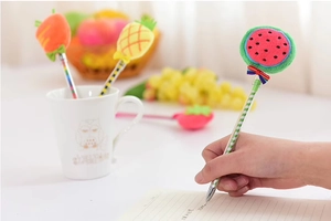 Primo piano di una mano che tiene una penna creativa con pompon di peluche a forma di anguria