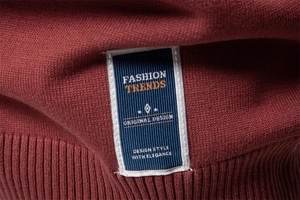 Detail of blue fashion tag stitched on the hem of a premium red knit sweater