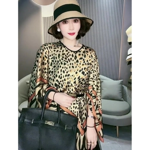 Details eines eleganten Seidenschals mit Leopardenmuster, kombiniert mit Strohhut