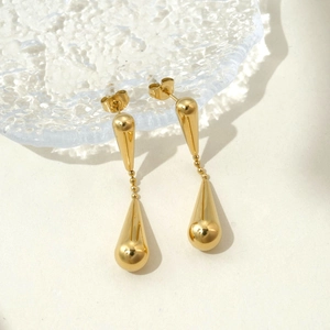 Detail showing the polished golden teardrop earrings with a mirror-like metallic finish
