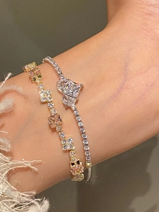 Detail of stacked zircon bracelets with gold and silver tones on a soft wrist background