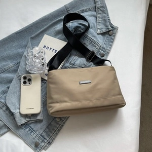 Detail of khaki nylon sling bag for men with adjustable strap on a lifestyle backdrop