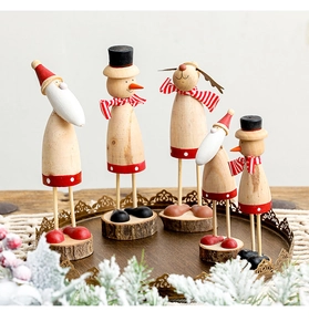 Detail of wooden Christmas figurines on a tray with snow-covered pine branches