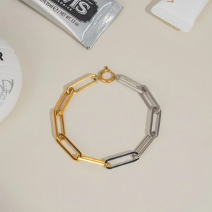 Detailed close-up of a two-tone gold and silver stainless steel chain bracelet with clasp