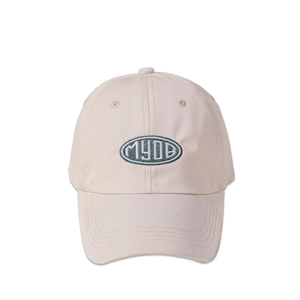Detailed close-up of the beige baseball cap with dark green MYDB embroidered oval patch