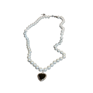 Faux pearl necklace with a black heart pendant and silver metal edge on white background