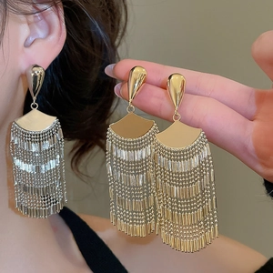 Macro shot of gold and silver fan-shaped fringe tassel earrings with long metallic chains