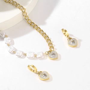 Detailed view of heart-shaped crystal pendant with baroque pearl necklace and matching earrings