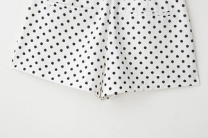 Gros plan détaillé d'un short blanc à pois noirs montrant les coutures de qualité et les poches