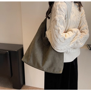 Detail shot of large olive green suede hobo shoulder bag shown on model's shoulder