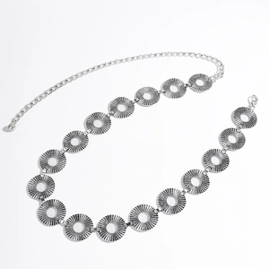 Detail of silver retro waist chain featuring sunburst engraved metal discs and lobster clasp