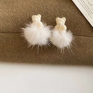 Close-up of flocking bear earring with pearl necklace detail and white plush ball