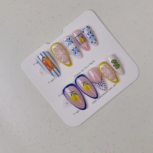 Detail of semi-handmade press-on nails with blue floral, fish, and lemon designs