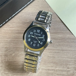 Detail view of quartz watch model 805 with silver stretch band and gold bezel on wood