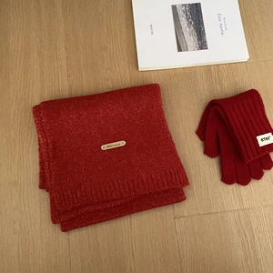 Detalle de conjunto de bufanda y guantes de invierno de punto grueso rojo sobre madera