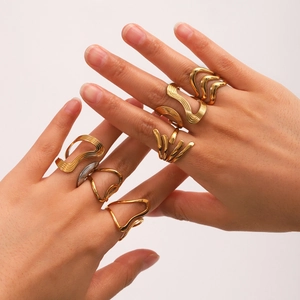 Close-up of stacked gold and silver wave rings on hand with a polished finish