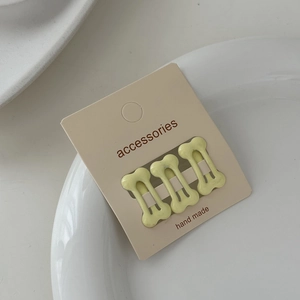 Three-piece set of cream yellow bone-shaped hair clips displayed on a white plate